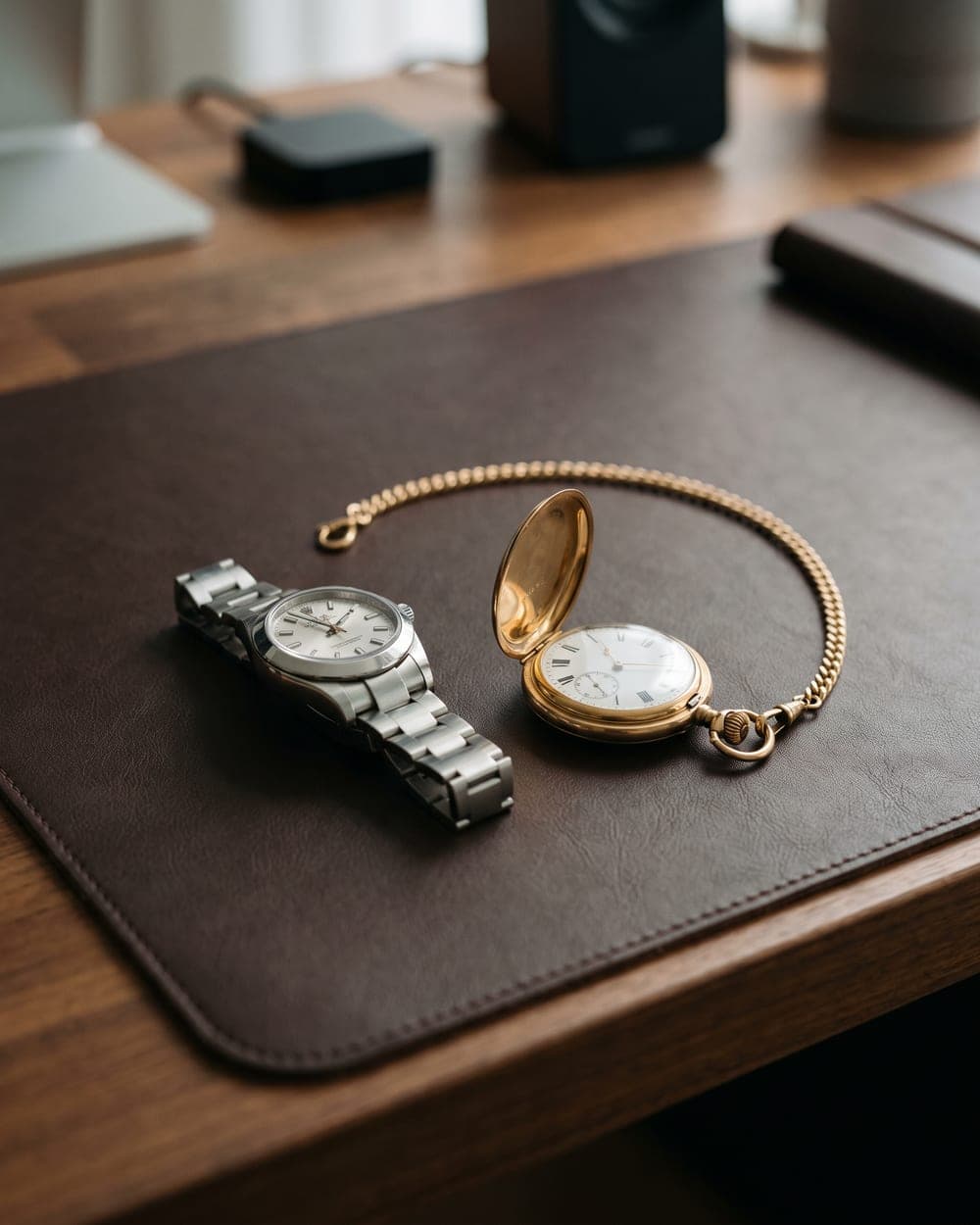 Luxus-Armbanduhr und offene goldene Taschenuhr mit Kette auf Ledermatte